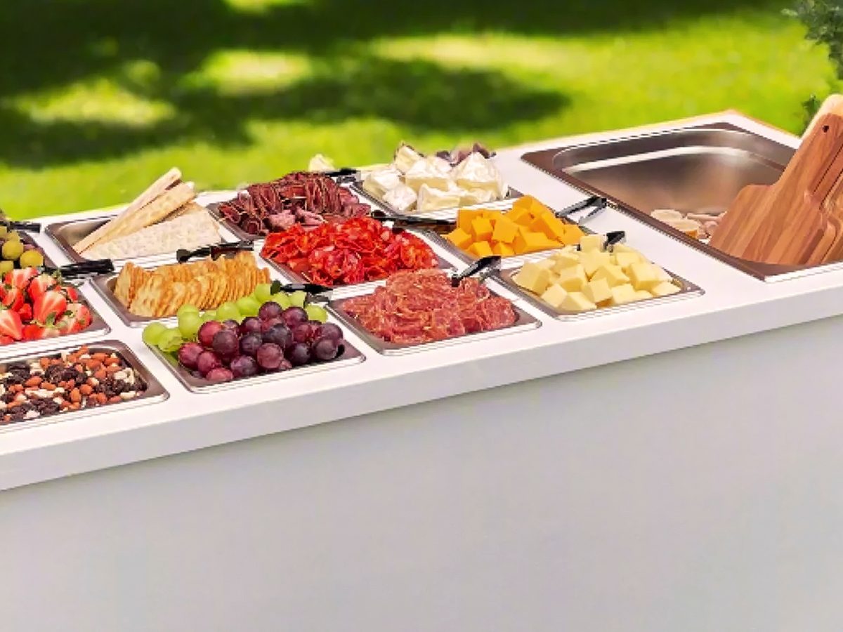 Sleek white mobile food cart with charcuterie and grazing items at an outdoor event
